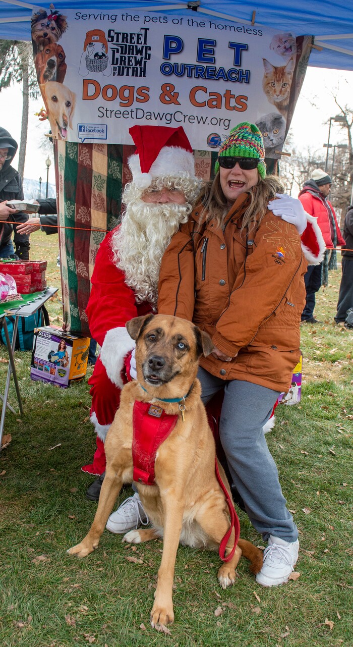 (Rick Egan  |  The Salt Lake Tribune)    Anne Cashatt, with dog Kiwi pose for a photo with Santqa, at the Street Dawg Crew Christmas outreach at Liberty Park Sunday.  The Street Dawg Crew supports the homeless and their pets every Sunday at Pioneer Park.  For today's Christmas Outreach, the Street Dawg Crew passed out food and gift bags for humans and animals, and also offered a photo opportunity with Santa. Sunday, Dec. 22, 2019.