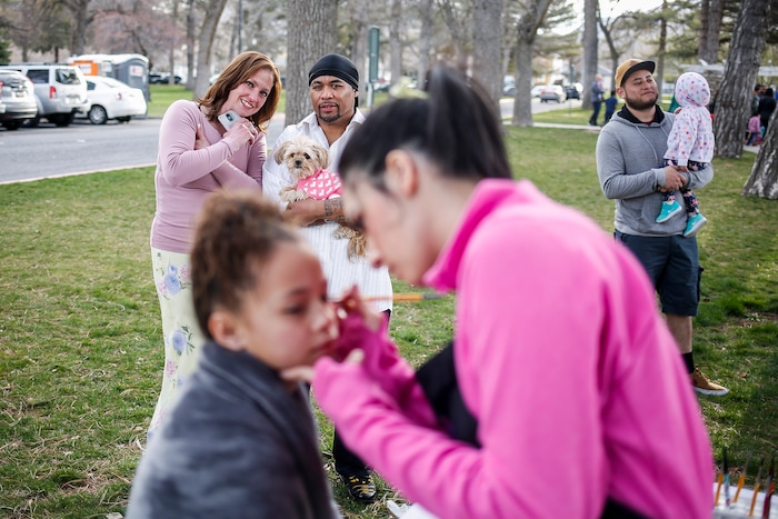 (Nicole Boliaux | For The Tribune) Kailee Brown, right, with My Kids Entertainment paints Aalyah Laeloni Milline's face while her parents watch during the annual Easter egg hunt put on by A Kid's Place Dentistry in Liberty Park in Salt Lake City on Saturday, March 31, 2018.