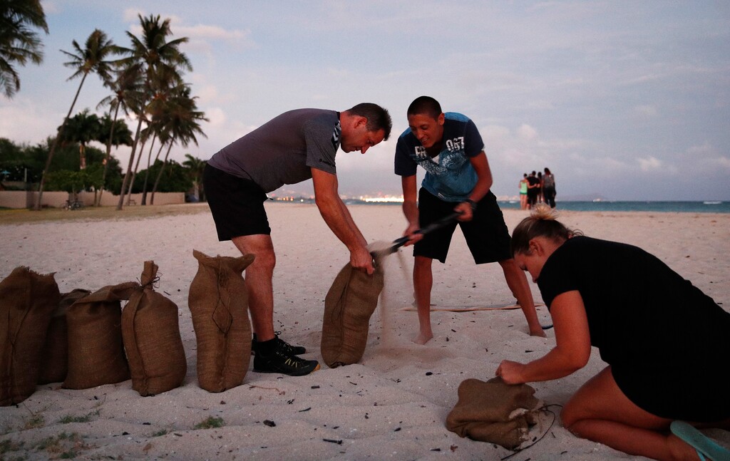 (AP Photo/John Locher) People, who declined to be named, fill up sand bags that will be used to help protect their home in preparation for Hurricane Lane, Wednesday, Aug. 22, 2018, along Ewa Beach in Honolulu. As emergency shelters opened, rain began to pour and cellphone alerts went out, the approaching hurricane started to feel real for Hawaii residents.