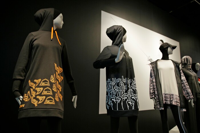 In this photo taken Thursday, Sept. 20, 2018, is a hooded knee-length dress at left made by Sarah Elenany for Muslim Girls, who wanted to participate in the Scout Association of the United Kingdom, in the exhibit Contemporary Muslim Fashions at the M. H. de Young Memorial Museum in San Francisco. The first major museum exhibition of contemporary Muslim women's fashion reflects designs from around the world that are vibrant and elegant, playful and diverse.  The exhibit opens on Saturday. (AP Photo/Eric Risberg)