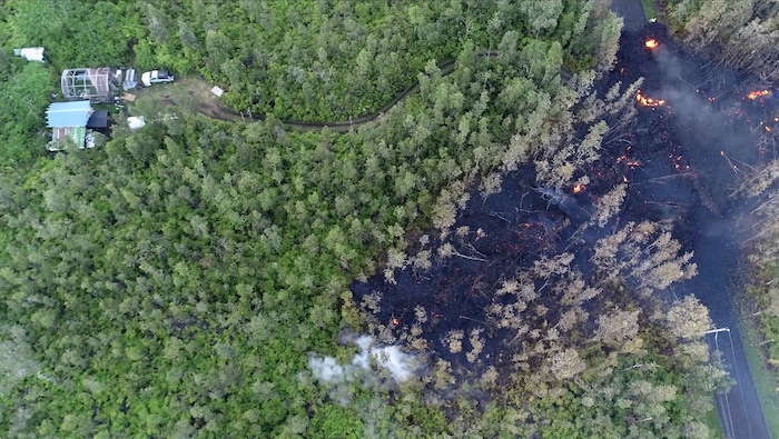 In this still frame taken from video, lava flows toward a home in the Puna District as a result of the eruption from Kilauea Volcano on Hawaii's Big Island Friday, May 4, 2018. The eruption sent molten lava through forests and bubbling up from paved streets and forced the evacuation of about 1,500 people who were still out of their homes Friday after Thursday's eruption. (Byron Matthews via AP)