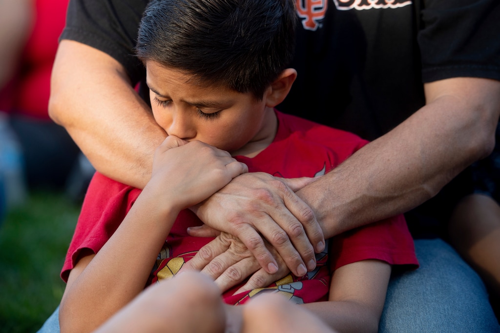 Robbie Ramirez, 10, holds onto his father, Robert Ramirez, during a vigil for victims of a Sunday evening shooting that left three people dead at the Gilroy Garlic Festival, Monday, July 29, 2019, in Gilroy, Calif. (AP Photo/Noah Berger)