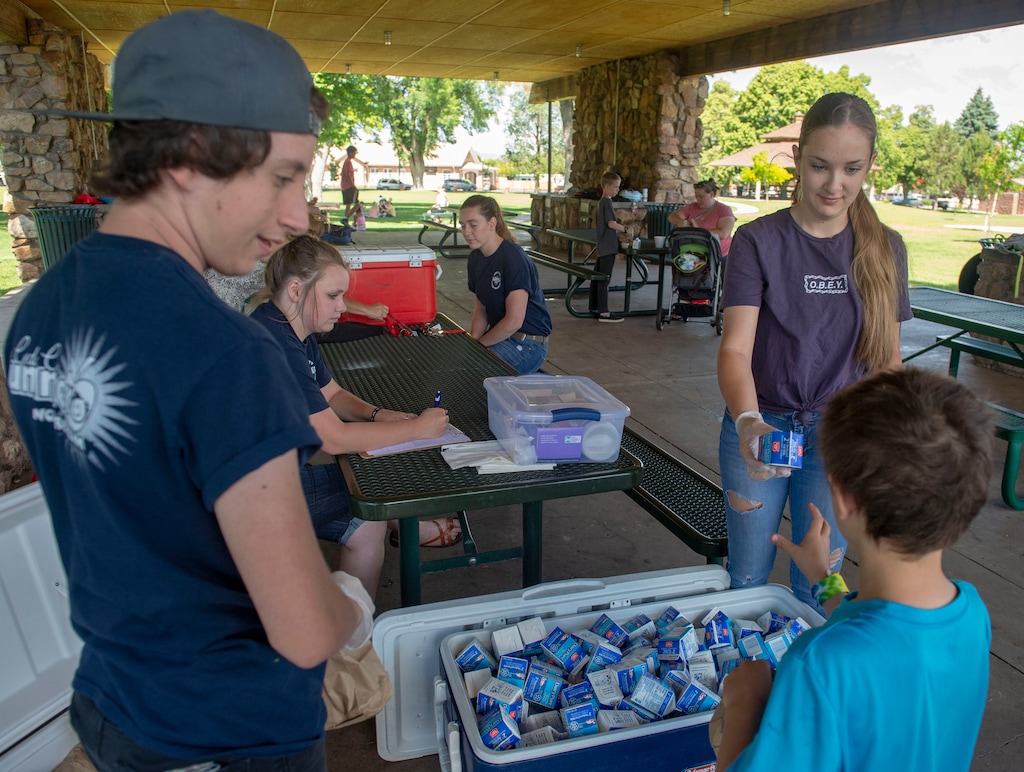 (Rick Egan  |  The Salt Lake Tribune)      Scott Nelson and Jessica Fahagun pass out the food and milk, during the Summer Sun Food and Fun summer lunch program in a park in Cedar City, Thursday, June 20, 2019. 