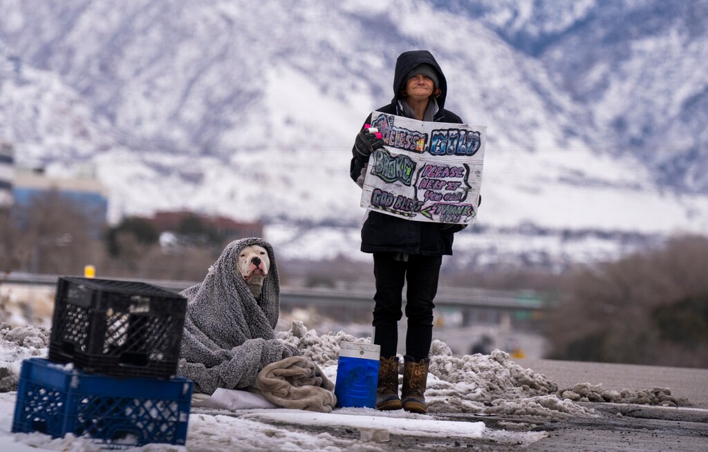 (Rick Egan | The Salt Lake Tribune)  A woman and her dog stand at the I-215 offramp, on Saturday, Jan. 13, 2024.