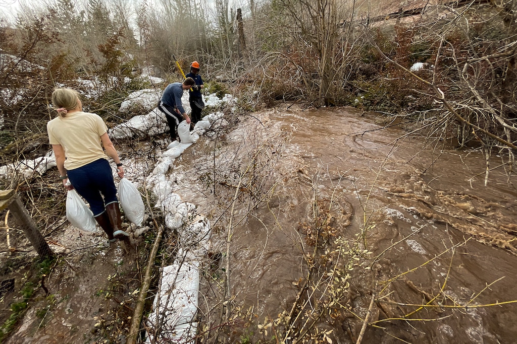 (Trent Nelson  |  The Salt Lake Tribune) Sarah McNurlin, Alex Klivecka and Jordan Hess put down sandbags as water rises sharply in Emigration Canyon on Wednesday, April 12, 2023.