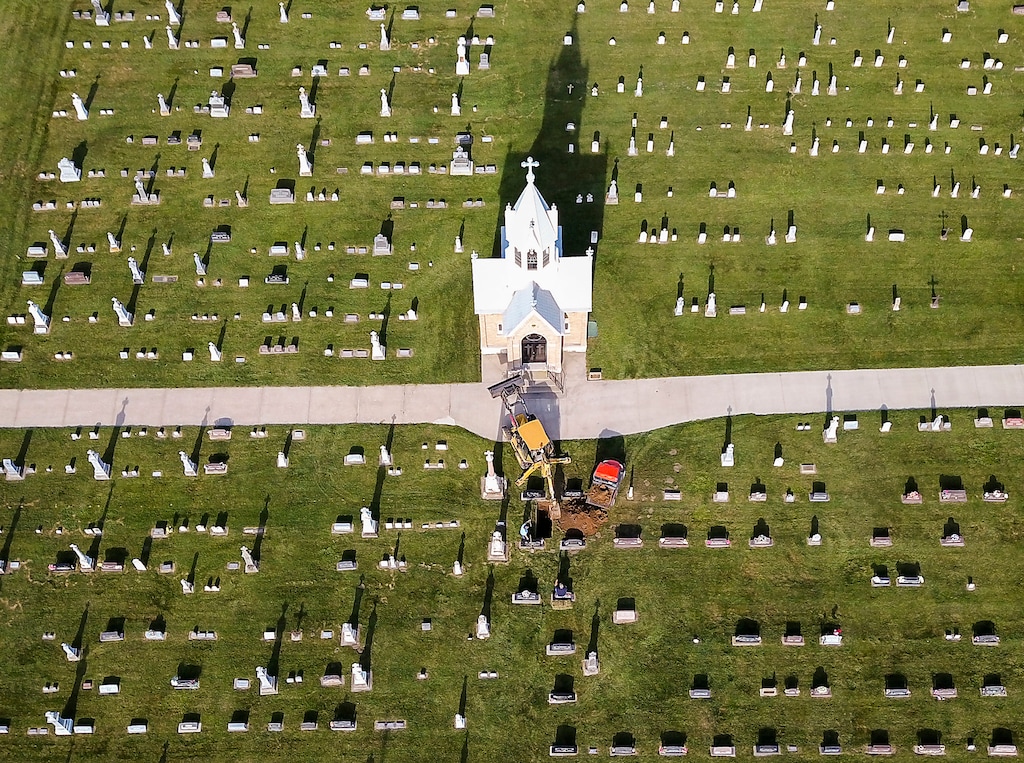 (Dave Kettering | Telegraph Herald via AP file) Workers dig a new grave at a church cemetery in New Vienna, Iowa, in August 2017.