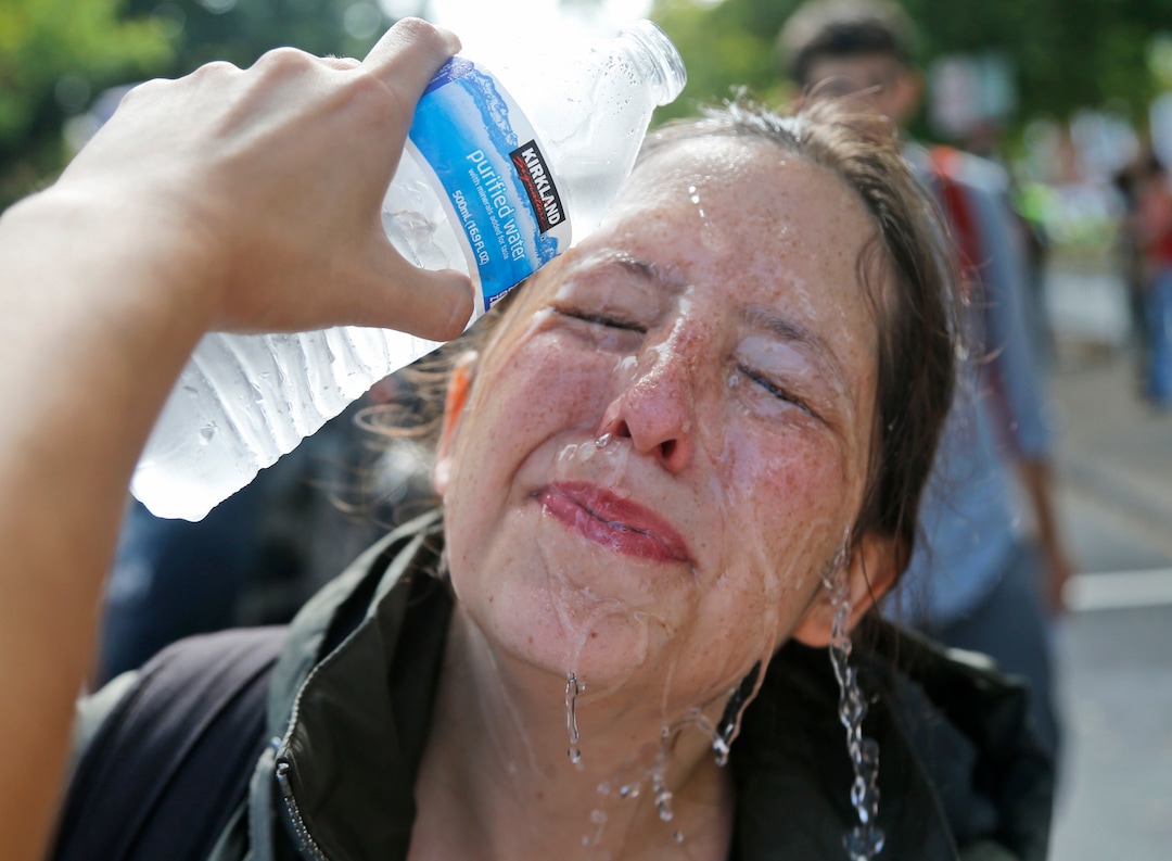 (Steve Helber  |  AP Photo)  A counter demonstrator gets a splash of water after being hit by pepper spray at the entrance to Lee Park in Charlottesville, Va., Saturday, Aug. 12, 2017. Gov. Terry McAuliffe declared a state of emergency and police dressed in riot gear ordered people to disperse after chaotic violent clashes between white nationalists and counter protestors.