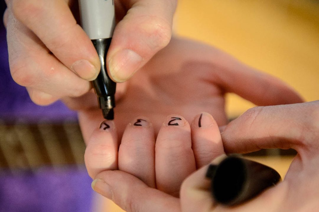 (Trent Nelson | The Salt Lake Tribune)  Guitar instructor Sofia Scott writes the numbers 1-4 on a new player's fingernails at Rock Camp for Womyn.