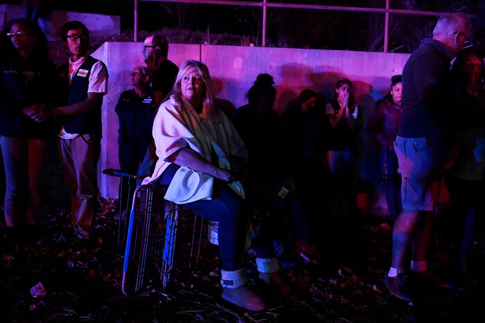 Darlene Jackson sits on an overturned shopping cart as she and fellow shoppers and employees gather outside after a gunman opened fire in Walmart in Thornton, Colo., Tuesday, Nov. 1, 2017. Police in Thornton announced the shooting in a tweet Wednesday evening and advised people to stay away from the area. Dozens of police cars and emergency vehicles converged at the store. (AAron Ontiveroz/The Denver Post via AP)