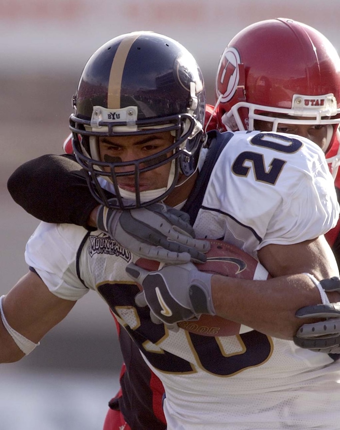 (Trent Nelson  |  Tribune File Photo)  BYU's Reno Mahe is brought down by Utah's Arnold Parker Saturday November 23, 2002 at Rice-Eccles Stadium.