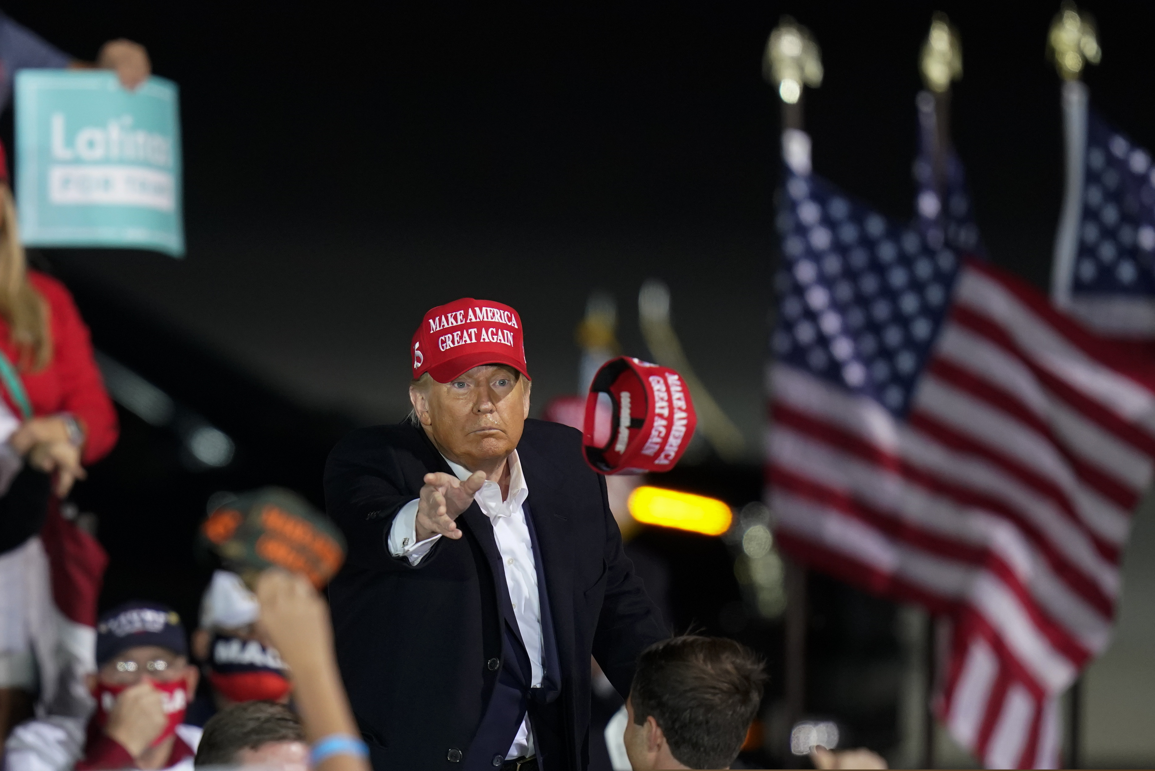 (Charlie Neibergall | AP file photo)  President Donald Trump throws a hat to a supporter during a campaign rally at Des Moines International Airport, Wednesday, Oct. 14, 2020, in Des Moines, Iowa.