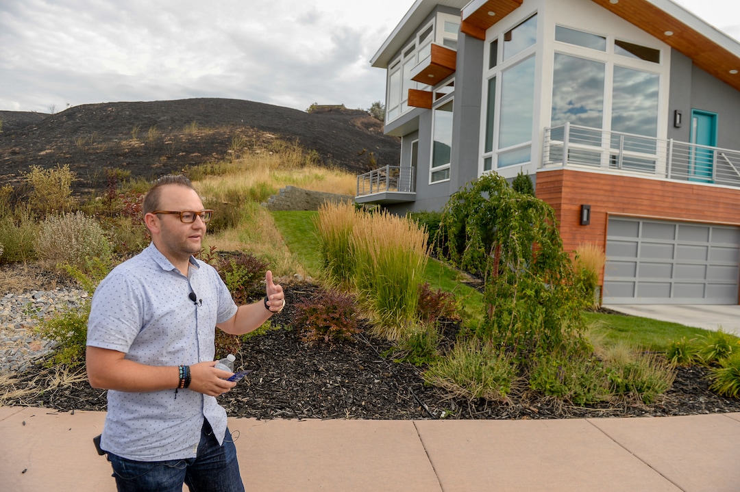 Leah Hogsten  |  The Salt Lake Tribune  Dustin Holt and his wife Jenna (not shown) sprayed water from garden hoses on Tuesday's grass fire that crept within 10feet of their home, at right. Five people were injured and one home was damaged by a fast-moving grass fire on Columbus Court, Tuesday, July 24, 2018. Forty homes were evacuated as flames spread through about 100 acres. Between 50 and 60 firefighters responded to the fire.
