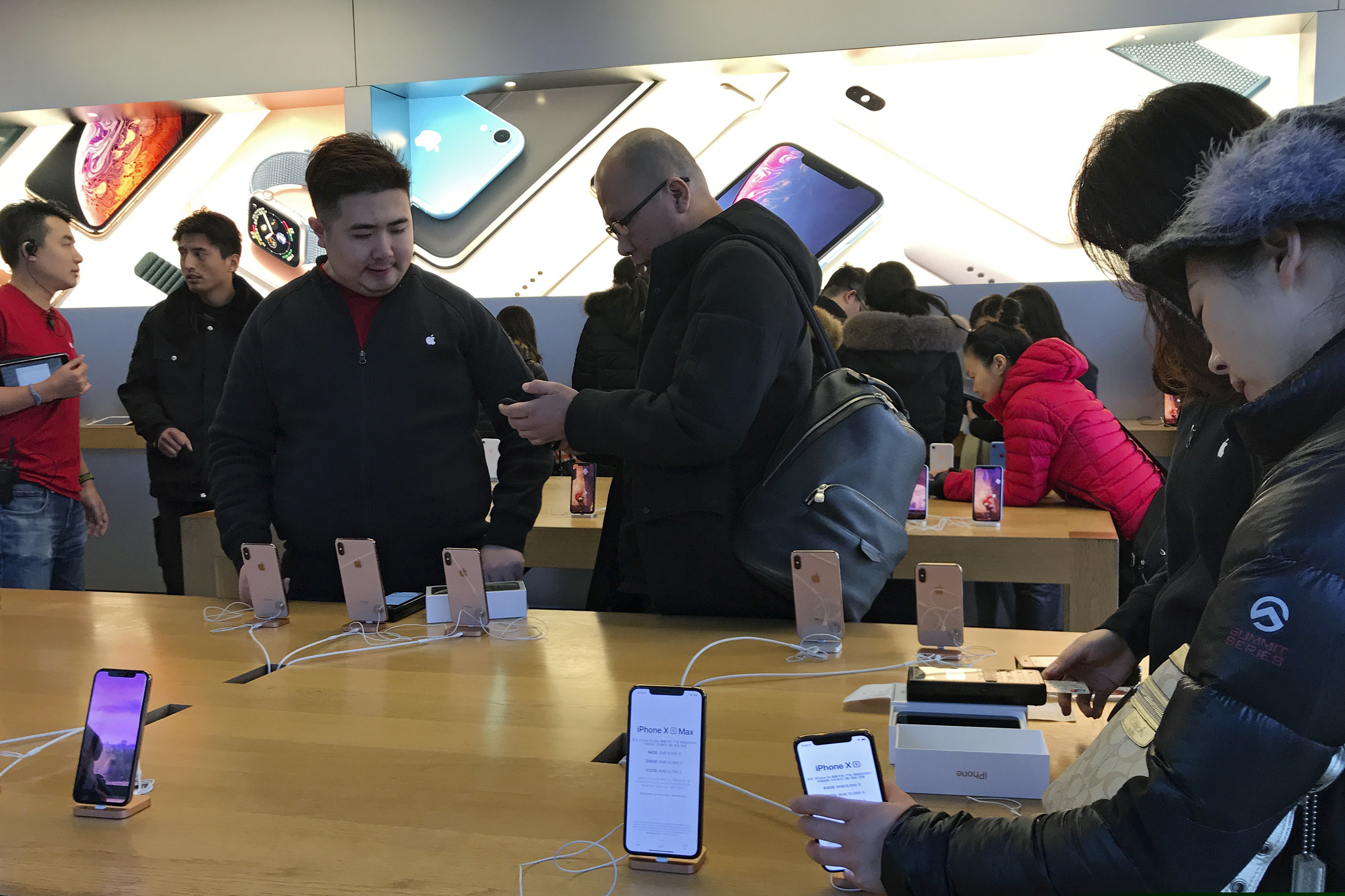 People buy the latest iPhone while others try out its latest model at an Apple Store in Beijing, Tuesday, Dec. 11, 2018. China's economy czar and the U.S. Treasury secretary discussed plans for talks on a tariff battle, the government said Tuesday, indicating negotiations are going ahead despite tension over the arrest of a Chinese tech executive. (AP Photo/Andy Wong)