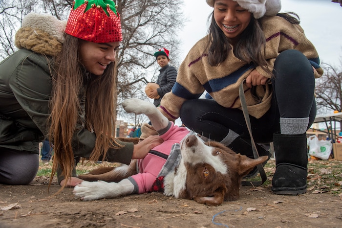 (Rick Egan  |  The Salt Lake Tribune)    Volunteers, Aitza Perez, 14, and Aimar Perez, 15, pet a dog named Victory, at the Street Dawg Crew Christmas outreach at Liberty Park Sunday.  The Street Dawg Crew supports the homeless and their pets  every Sunday at Pioneer Park. Today besides  passing out food and gift bags for humans and animals, they offered a photo opportunity with Santa. Sunday, Dec. 22, 2019. For the Christmas Outreach today, the Crew they offered a photo opportunity with Santa. Sunday, Dec. 22, 2019.