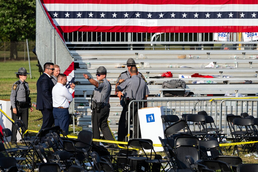 (Eric Lee | The New York Times) Law enforcement officers confer after a shooting at a campaign rally for former President Donald Trump in Butler, Pa., on Saturday, July 13, 2024.