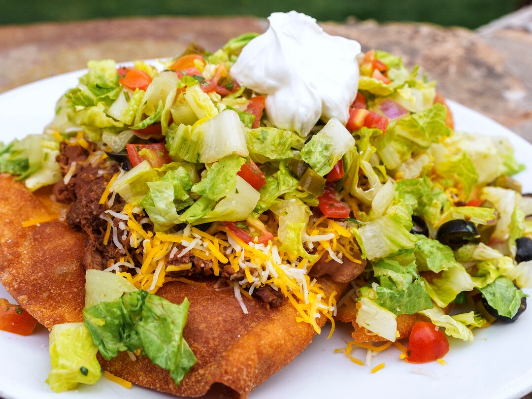 (Leah Hogsten | The Salt Lake Tribune) Emigration Cafe's Navajo Taco Salad with heirloom beans, braised chile beef, lettuce, avocado, pico, sour cream, cheddar jack, iceberg on sourdough frybread, April 27, 2022. Emigration Cafe's menu features Roman style wood fired pizza, salads, sandwiches and mains.