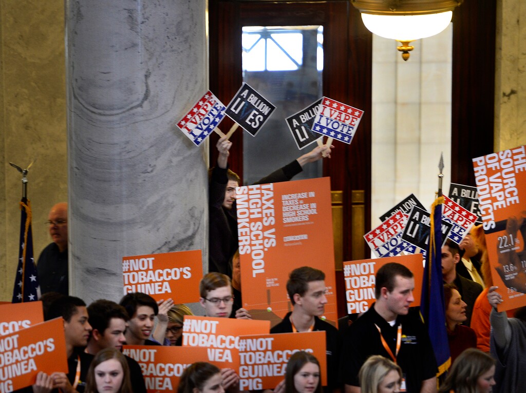 (Scott Sommerdorf | Tribune file photo)
A pro e-cigarette supporter holds "I VAPE - I VOTE" signs behind the large "OUTRAGE!" group who were there to push for a bill that would change the allowed age to buy tobacco products from 19 to 21 during a rally in the Utah Capitol Rotunda, February 17, 2016.