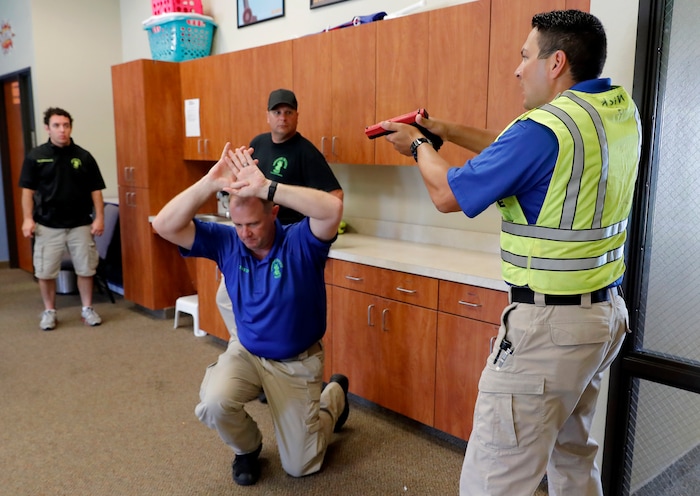 (Tony Gutierrez | AP Photo) In this July 21, 2019 photo, Police officers David Riggall, kneeling, and Nick Guadarrama, right, instruct students Bryan Hetherington, left rear, and Chris Scott, center rear, during a security training session at Fellowship of the Parks campus in Haslet, Texas. While recent mass shootings occurred at a retail store in El Paso, Texas, and a downtown entertainment district in Dayton, Ohio, they were still felt in houses of worship, which haven’t been immune to such attacks. And some churches have started protecting themselves with guns.