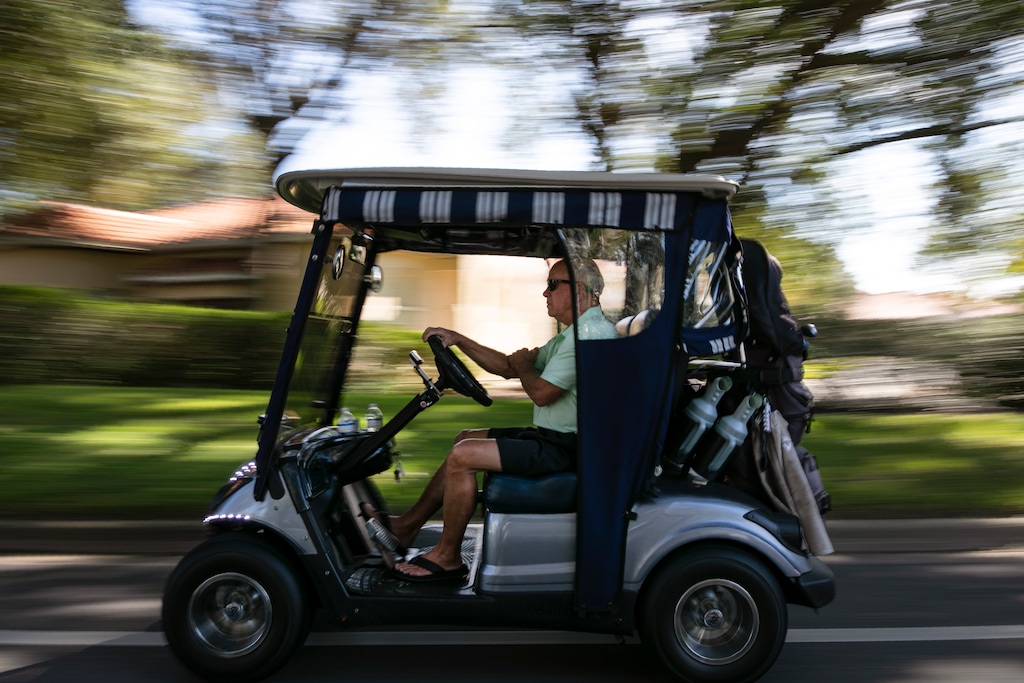 (Wong Maye-E | AP file photo) John Vai drives his golf cart through The Villages, Fla., on, Nov. 21, 2019. The city where many retirees live has more golf carts than cars on many of its roads.