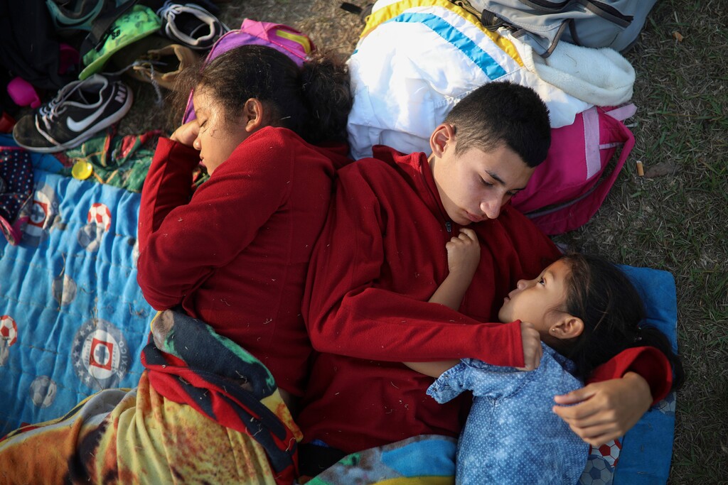 The Zelaya siblings, from El Salvador, Nayeli, right, Anderson, center, and Daniela, huddle together on a soccer field, at the sports club where Central American migrants traveling with the annual "Stations of the Cross" caravan are camped out, in Matias Romero, Oaxaca State, Mexico, Wednesday, April 4, 2018. The children's father Elmer Zelaya, 38, said the family is awaiting temporary transit visas that would allow them to continue to the U.S. border, where they hope to request asylum and join relatives in New York.(AP Photo/Felix Marquez)