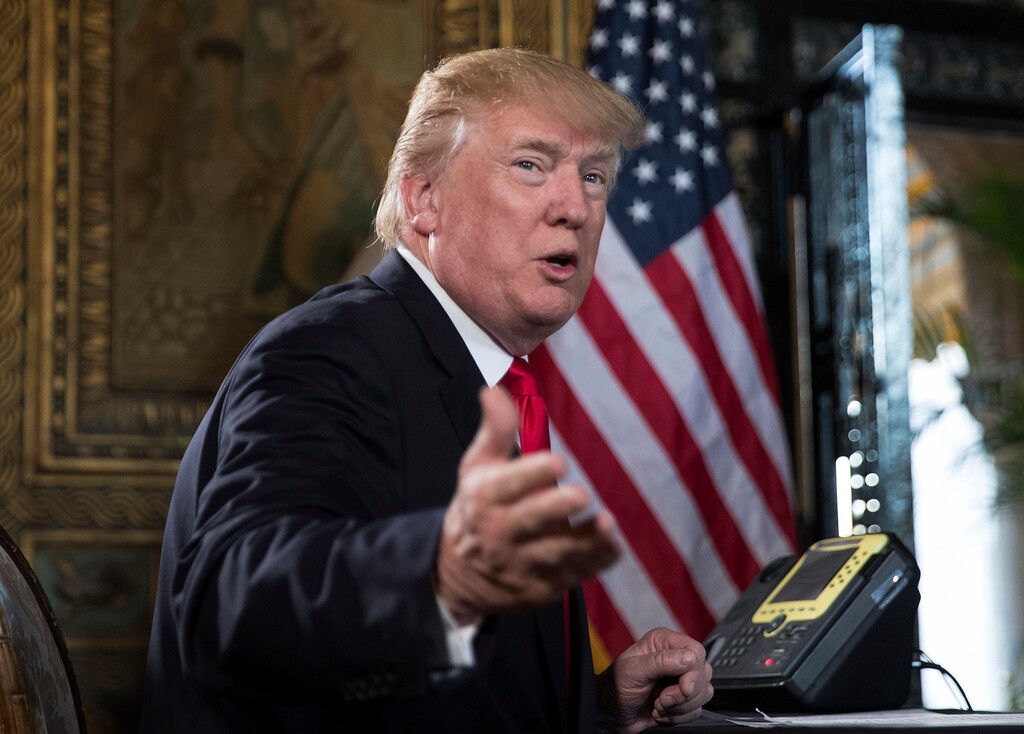 FILE - In a Sunday, Dec. 24, 2017 file photo, President Donald Trump turns to talk to the gathered media during a Christmas Eve video teleconference with members of the mIlitary at his Mar-a-Lago estate in Palm Beach, Fla. President Donald Trump is criticizing the U.S. Postal Service, saying the agency is “losing many billions of dollars a year” and asking why it is “charging Amazon and others so little to deliver their packages.” Trump tweeted Friday, Dec. 29, that the post office “should be charging MUCH MORE!” (AP Photo/Carolyn Kaster, File)
