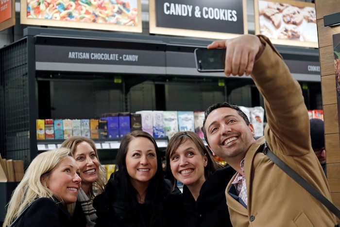 Amazon employees, who declined to be identified, and friends gather for a selfie inside an Amazon Go store, Monday, Jan. 22, 2018, in Seattle. More than a year after it introduced the concept, Amazon opened its artificial intelligence-powered Amazon Go store in downtown Seattle on Monday. (AP Photo/Elaine Thompson)