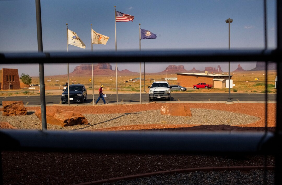 (Leah Hogsten  |  The Salt Lake Tribune)  Monument Valley Health Clinic pharmacy runner Delbert Dixon, above in red, hustles in and out of the building, delivering medications to patients sitting in their cars Aug., 24, 2020. Like the three other Utah Navajo Health System clinics in San Juan County, patients are required to remain in their car whether they have an appointment with the doctor or are there to pick up prescription refills.