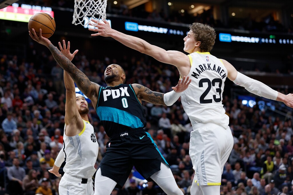 Portland Trail Blazers guard Damian Lillard (0) drives to the basket against Utah Jazz guard Johnny Juzang, left, and Utah Jazz forward Lauri Markkanen (23) during an NBA basketball game, Wednesday, March 22, 2023, in Salt Lake City. (AP Photo/Jeff Swinger)