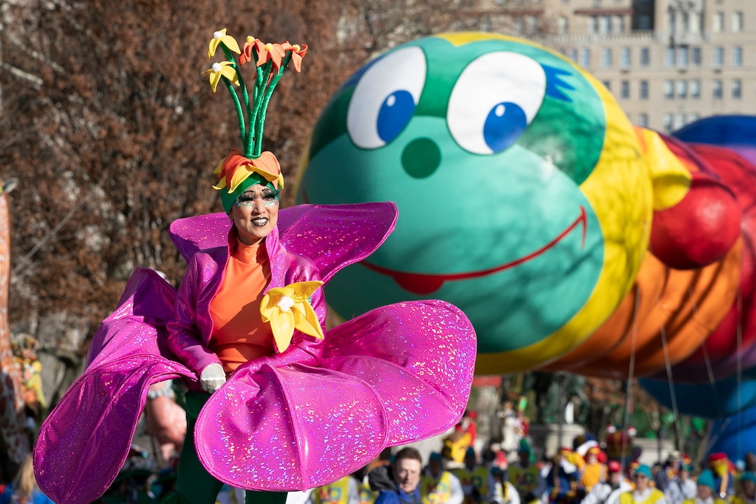 (Mark Lennihan | AP)  A woman in a flower costume marches in front of the Wiggle Worm balloon during the Macy's Thanksgiving Day Parade, Thursday, Nov. 28, 2019, in New York.