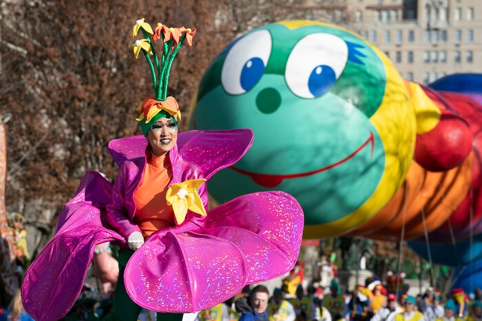 (Mark Lennihan | AP) A woman in a flower costume marches in front of the Wiggle Worm balloon during the Macy's Thanksgiving Day Parade, Thursday, Nov. 28, 2019, in New York.