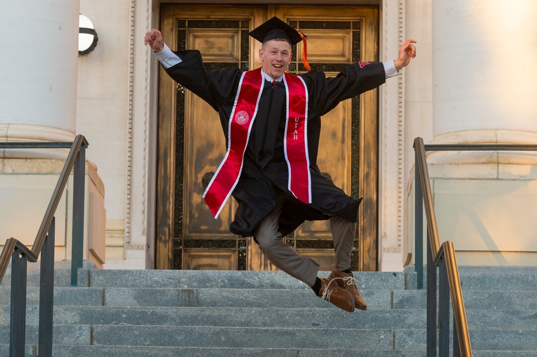 (Rick Egan  |  The Salt Lake Tribune)    Spencer Brewster leaps in the air for a graduation picture in front of the Park Building at the University of Utah, Thursday April 30, 2020