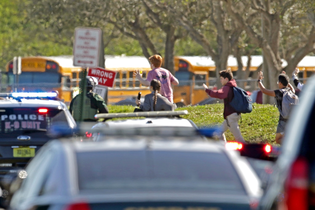 FILE - In this Feb. 14, 2018 file photo, students run with their hands in the air following a shooting at Marjory Stoneman Douglas High School in Parkland, Fla. Florida authorities released video showing the chaos and heroism that took place outside a building during the high school massacre. The Broward Sheriff’s Office released videos Wednesday, Aug. 22 from five cameras surrounding the building at Marjory Stoneman Douglas High School where 17 died Feb. 14. The silent videos show blurred images of students running from the building.  (John McCall /South Florida Sun-Sentinel via AP, File)