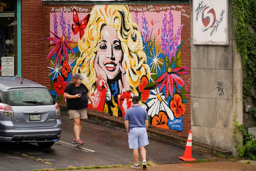 People look at a mural of Dolly Parton outside The 5 Spot, a music club in Nashville, Tenn., Friday, Aug. 21, 2020. Artist Kim Radford said Dolly fans from around the world have contacted her about the mural, which contains a quote from Parton about her support for the Black Lives Matter movement. (AP Photo/Mark Humphrey)