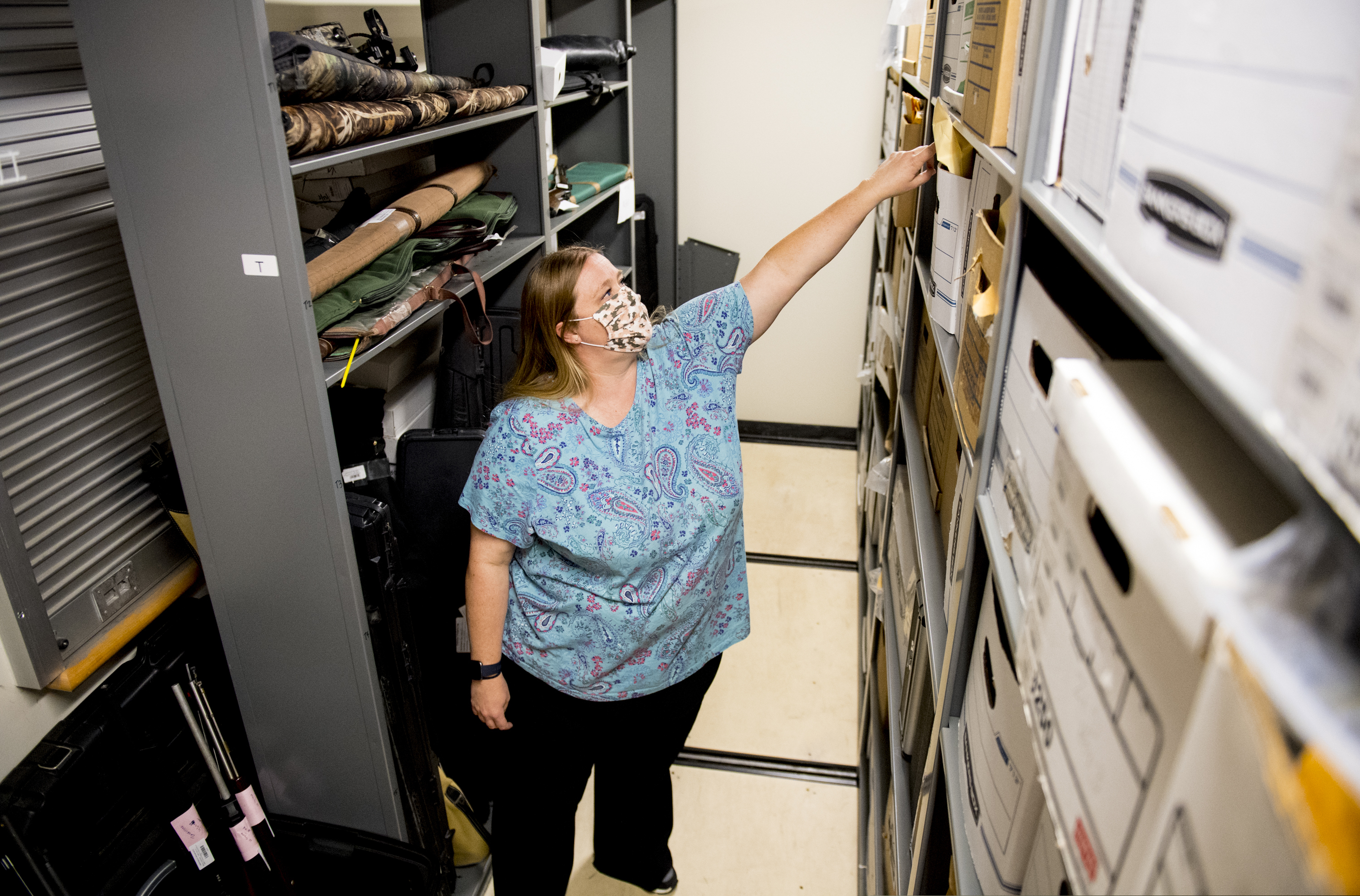 (Isaac Hale | The Daily Herald via AP) Evidence technician Tara Calancea reaches for a box beside a collection of firearms in the Orem Police Department's evidence room Thursday, Sept. 17, 2020, in Orem.