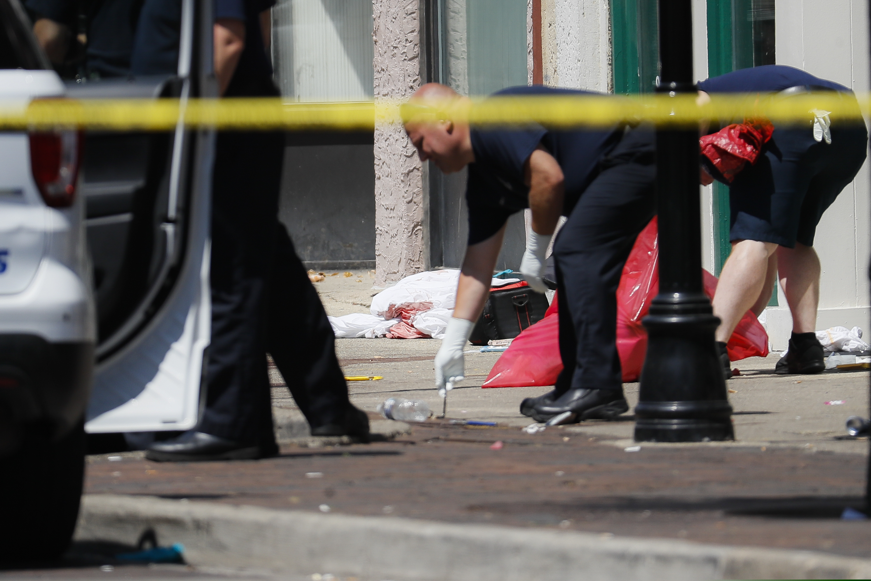 Authorities remove bloody rags and debris at the scene of a mass shooting, Sunday, Aug. 4, 2019, in Dayton, Ohio. Multiple people in Ohio have been killed in the second mass shooting in the U.S. in less than 24 hours, and the suspected shooter is also deceased, police said. (AP Photo/John Minchillo)