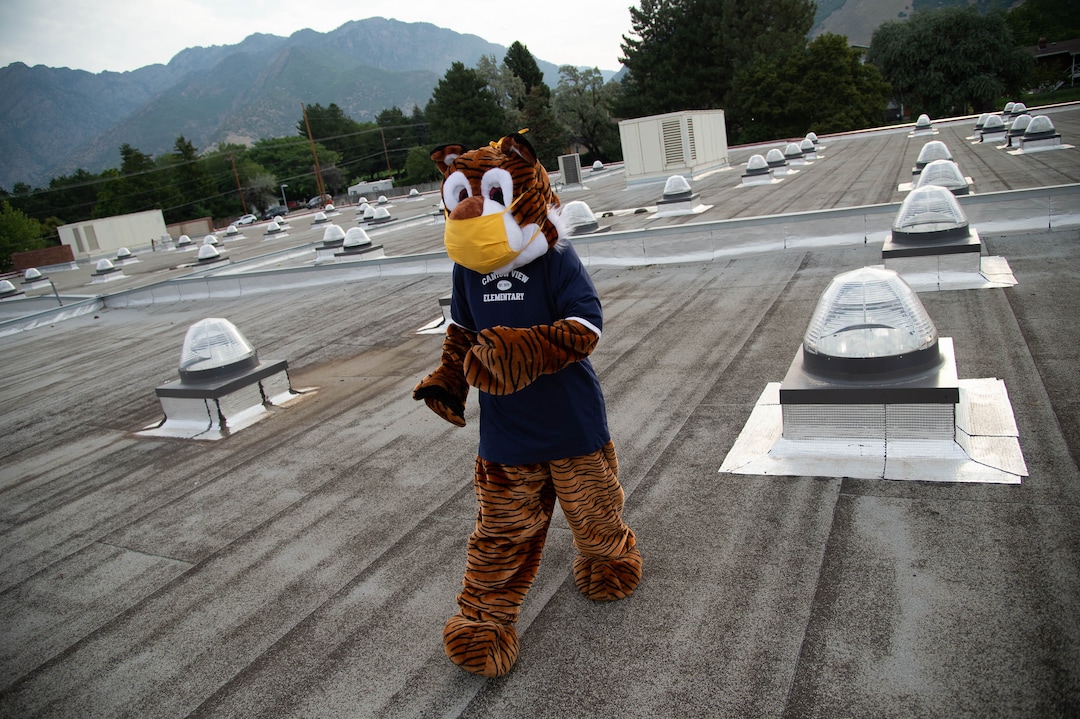 (Francisco Kjolseth  |  The Salt Lake Tribune) Home of the Cubs, Canyon View Elementary school mascot Bennie, played by PTA president Emily Weigel, gets gets ready to welcome students back from the roof of the school. It was the first day of classes for the Canyons School District on Monday, August 24, 2020.
