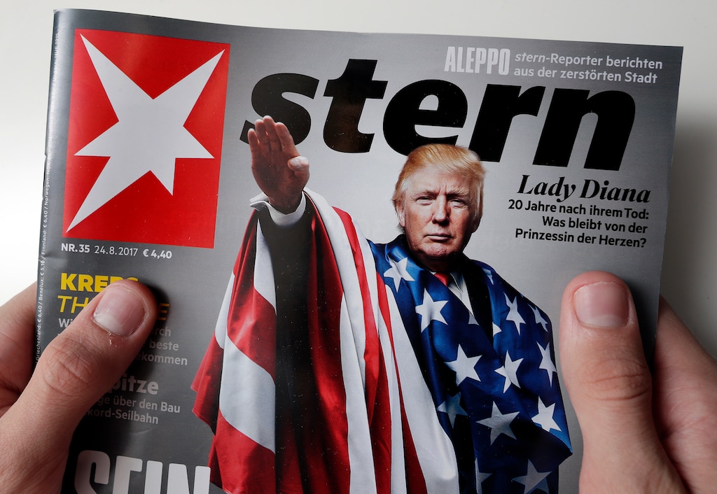 A person holds a copy of the 'Stern' news magazine in Berlin, Germany, Friday, Aug. 25, 2017 showing U.S. President Donald Trump draped in the American flag while giving a stiff-armed Nazi salute. (AP Photo/Michael Sohn)