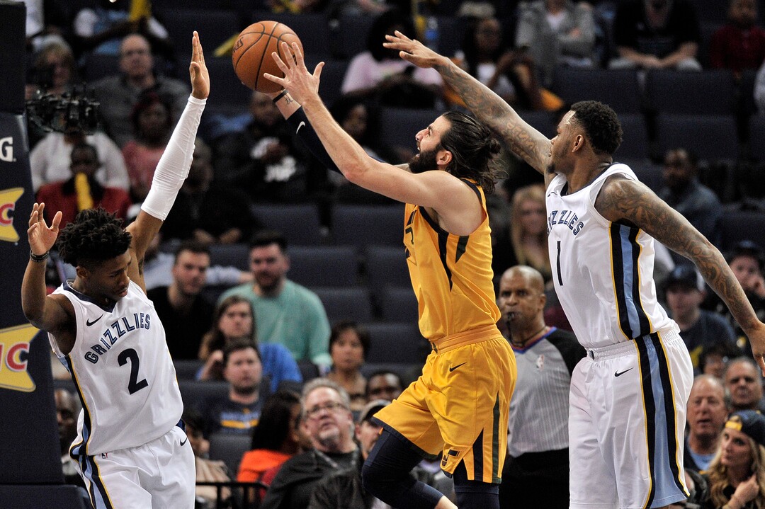 Utah Jazz guard Ricky Rubio, center, shoots between Memphis Grizzlies forward Jarell Martin (1) and guard Kobi Simmons (2) in the second half of an NBA basketball game Friday, March 9, 2018, in Memphis, Tenn. (AP Photo/Brandon Dill)