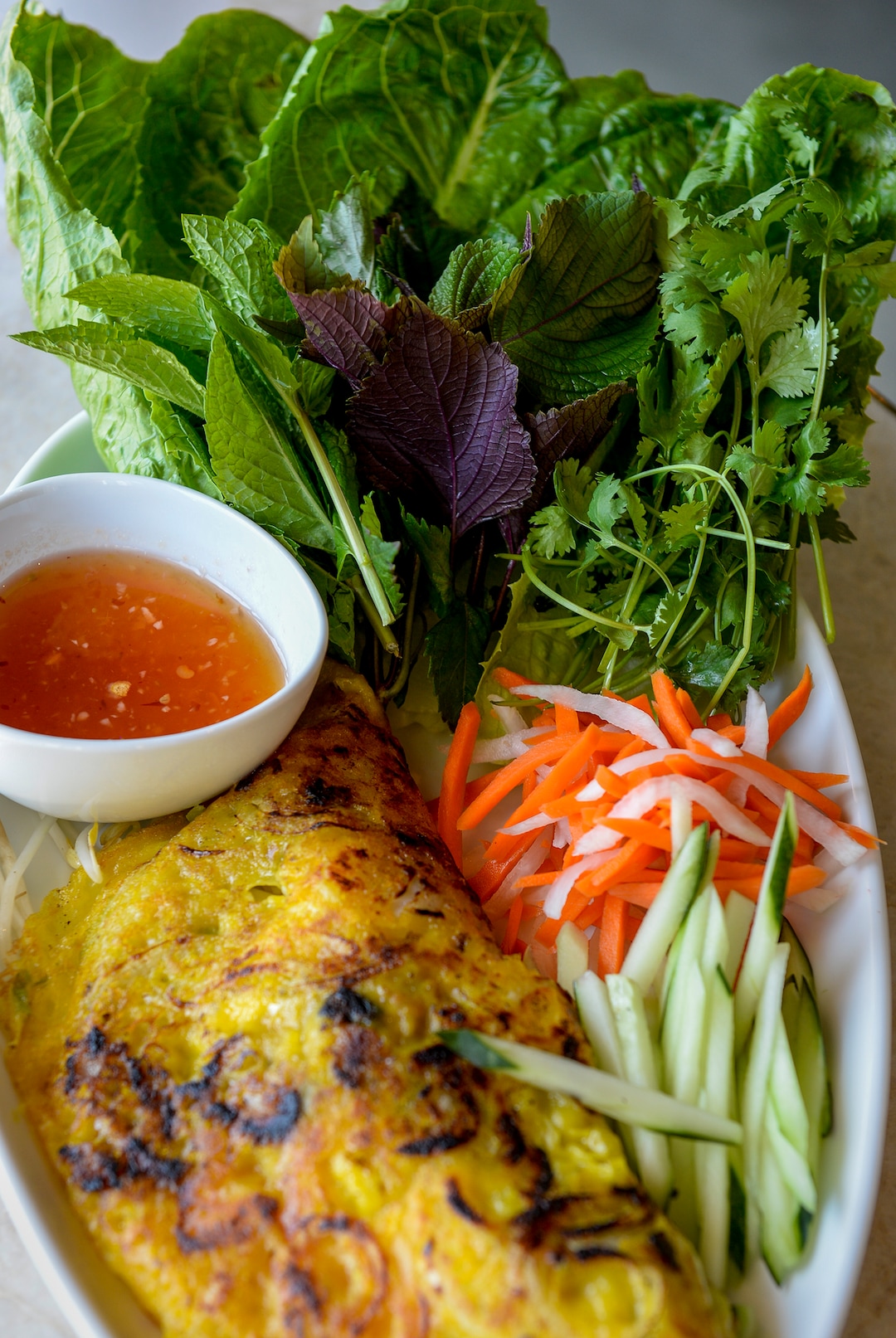 (Leah Hogsten  |  The Salt Lake Tribune)  Saola's Saigon sizzling crepe made with coconut milk, tumeric, rice flour crepe batter, bean sprouts, mungbean, scallion, pork belly, prawns stuffing, served with garden herbs and lime chili dip. Saola restaurant, located in Cottonwood Heights, serves Vietnamese food using locally sourced ingredients.