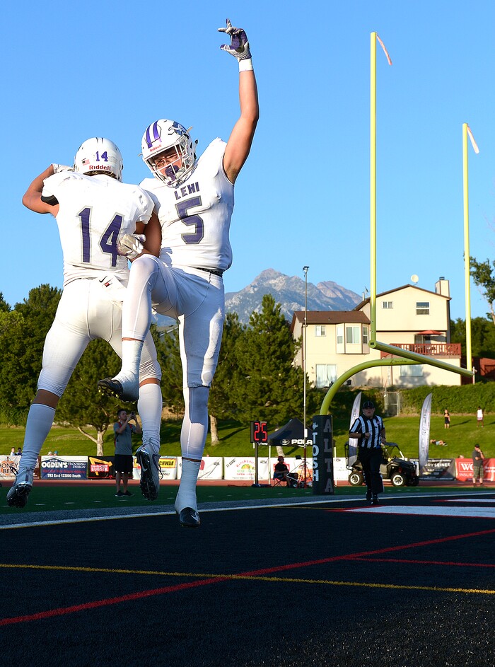 (Leah Hogsten  |  The Salt Lake Tribune) Lehi's Jaxon Moody (14) and Dallin Holker (5) celebrate Holker's  touchdown in the first half.  Lehi High School and Alta High School are tied, 42-42 in the second half during their game, Friday, August 18, 2017 in Sandy. 