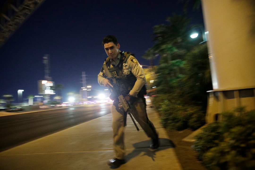A police officer runs along a sidewalk near a shooting near the Mandalay Bay resort and casino on the Las Vegas Strip, Sunday, Oct. 1, 2017, in Las Vegas. (AP Photo/John Locher)