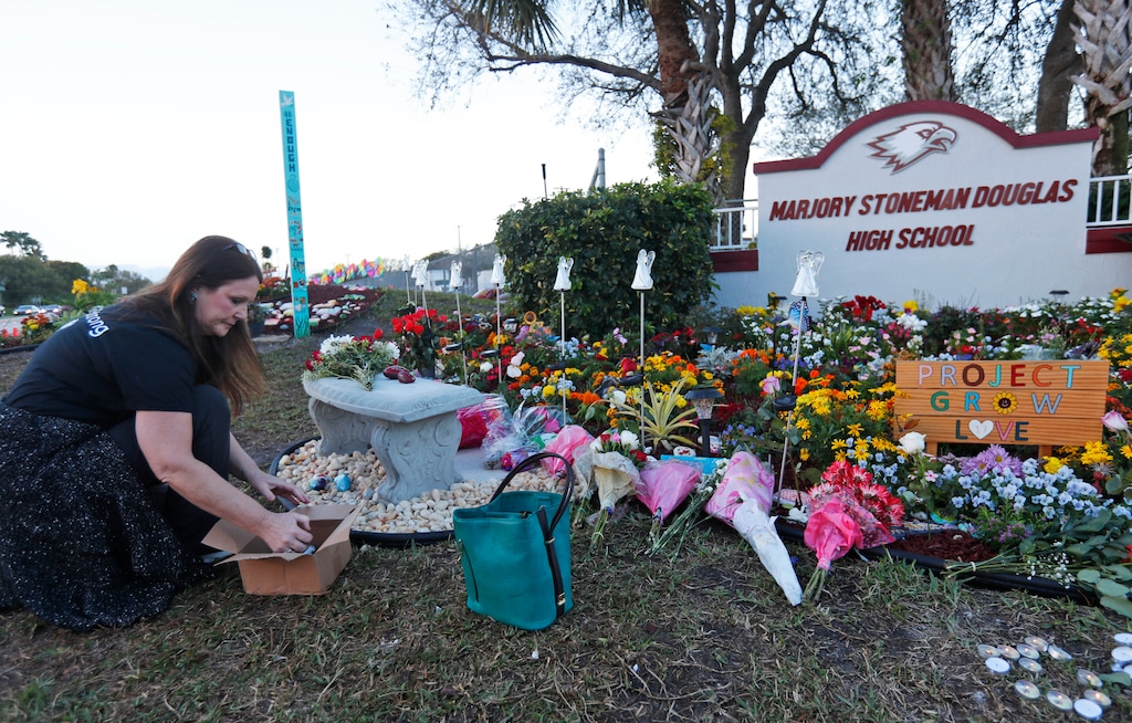 (Wilfredo Lee | AP file photo)
In this Feb. 14, 2019, photo, Suzanne Devine Clark, an art teacher at Deerfield Beach Elementary School, places painted stones at a memorial outside Marjory Stoneman Douglas High School during the firstr anniversary of the school shooting in Parkland, Fla. It’s been more than 1,000 days since a gunman with an AR-15 rifle burst into a Florida high school, killing 17 people and wounding 17 others.