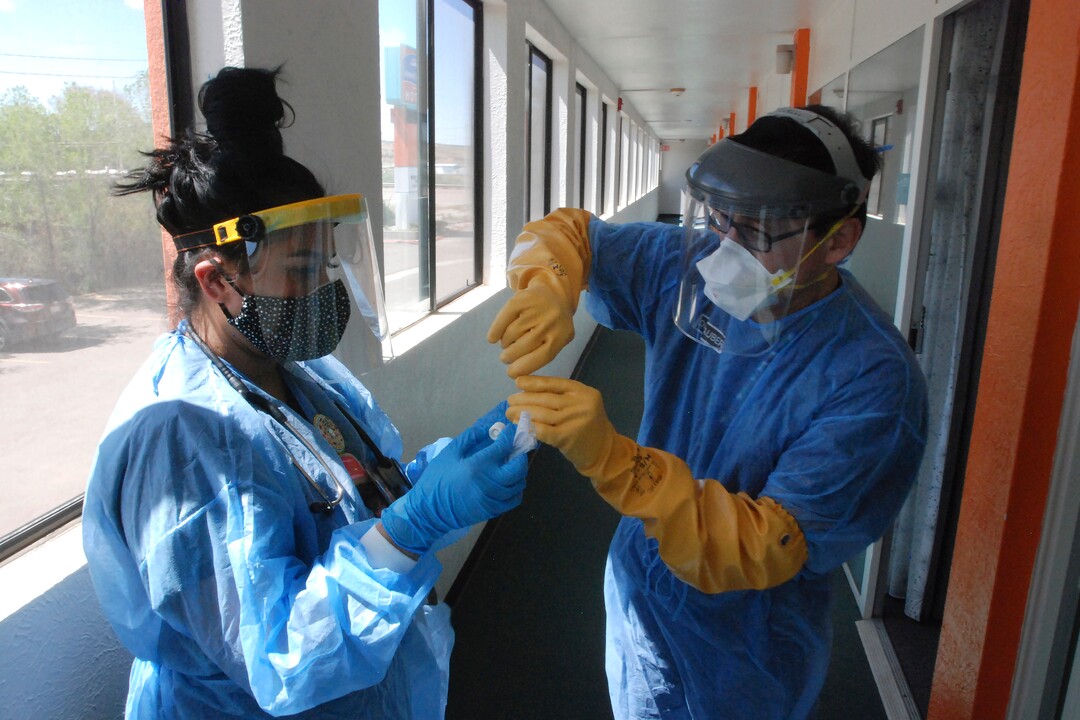 FILE - In this May 7, 2020, file photo, Certified Medical Assistant Shaniya Wood, left, and physician Caleb Lauber, right, test one of over 100 homeless patients who were being isolated in motels for the coronavirus in Gallup, N.M. Some 140 people are participating in the impromptu system, and officials hope it will interrupt a treadmill of infections among Gallup’s homeless population. (AP Photo/Morgan Lee, File)