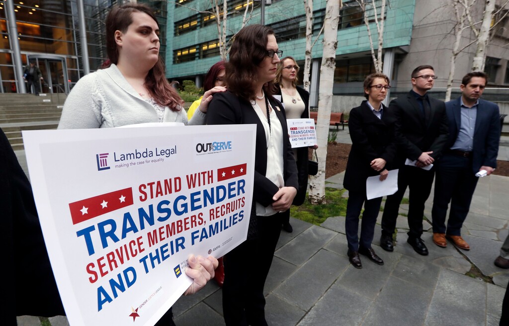 Plaintiffs Cathrine Schmid, second left, and Conner Callahan, second right, listens with supporters during a news conference in front of a federal courthouse following a hearing there Tuesday, March 27, 2018, in Seattle. (AP Photo/Elaine Thompson)