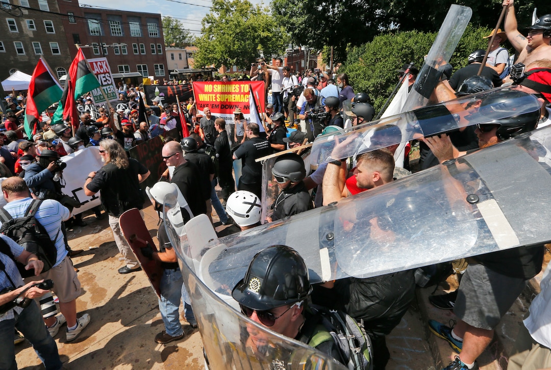 White nationalist demonstrators use shields as they clash with counter demonstrators at the entrance to Lee Park in Charlottesville, Va., Saturday, Aug. 12, 2017.   Hundreds of people chanted, threw punches, hurled water bottles and unleashed chemical sprays on each other Saturday after violence erupted at a white nationalist rally in Virginia. At least one person was arrested.  (AP Photo/Steve Helber)