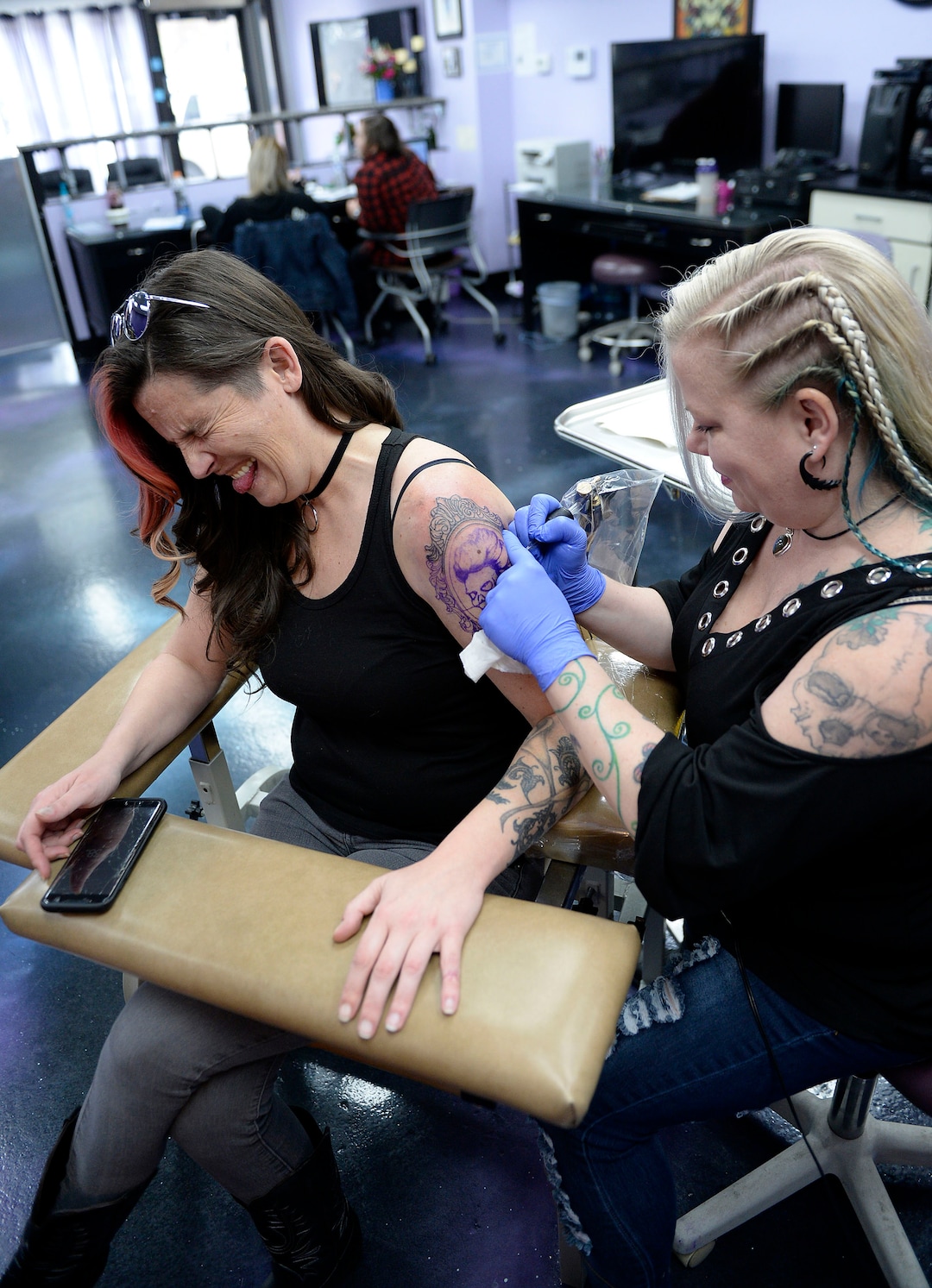 (Al Hartmann  |  The Salt Lake Tribune) 	Terrina Francis, tatoo artist and owner of Fallen Angel Tattoo, is Salt Lake's only all-women tattoo studio.  She works on a personal tattoo for Shannon Gibbs, left.  Gibbs squints in momentary pain as she hits a senstivie part of her arm.   The design is an old-fashioned cameo skull that she has thought about and wanted for four years.   Francis also offers to tattoo over scars and disfigurements due to domestic violence, breast cancer, and burns.   The shop offers a place where women can feel comfortable about getting tattooed in a very male-dominated field. 