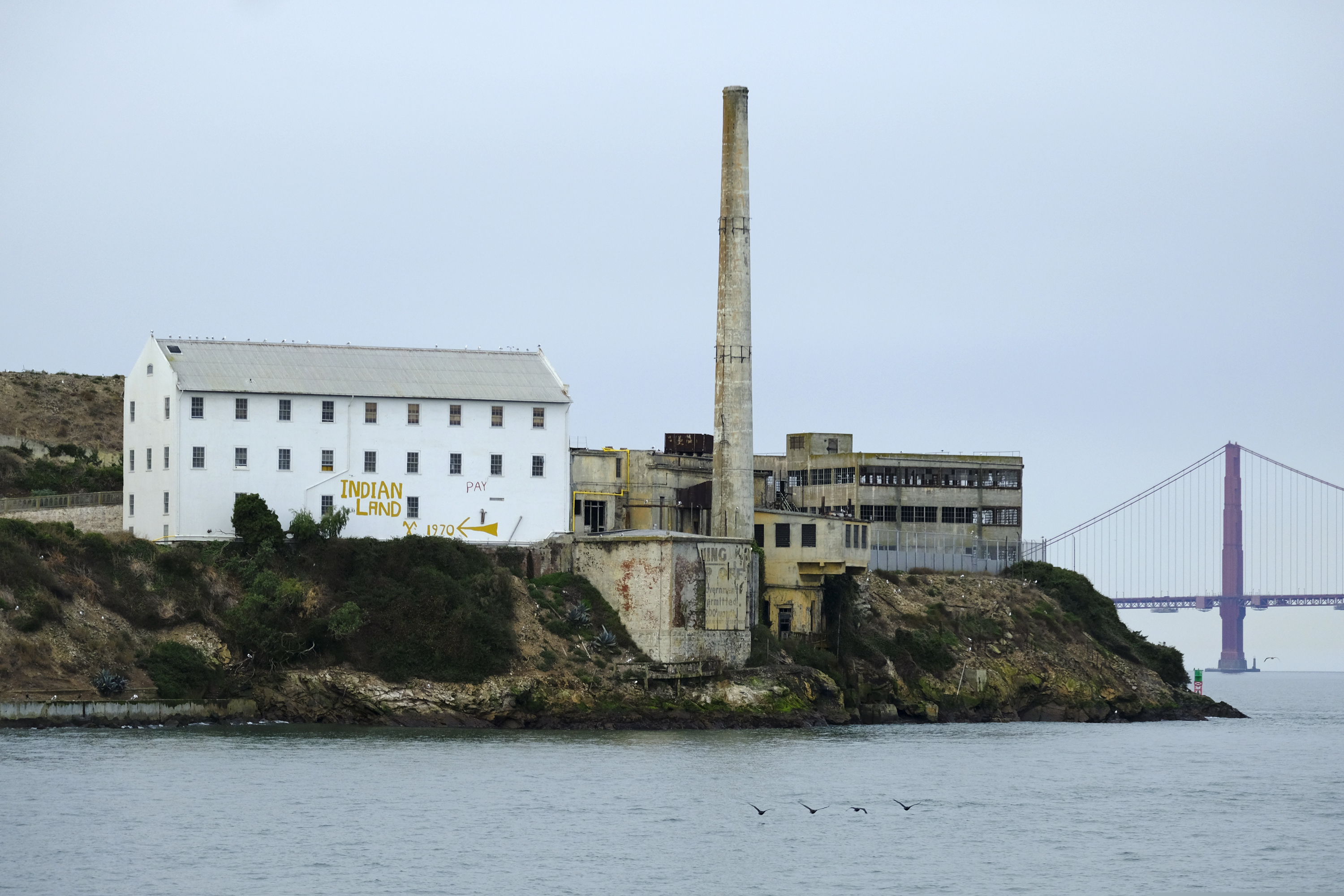 (Eric Risberg | AP) In this photo taken Friday, Nov. 15, 2019, the words "Indian Land" are painted on a building on Alcatraz Island with the Golden Gate Bridge in the background in San Francisco. The week of Nov. 18, 2019, marks 50 years since the beginning of a months-long Native American occupation at Alcatraz Island in the San Francisco Bay. The demonstration by dozens of tribal members had lasting effects for tribes, raising awareness of life on and off reservations, galvanizing activists and spurring a shift in federal policy toward self-determination.