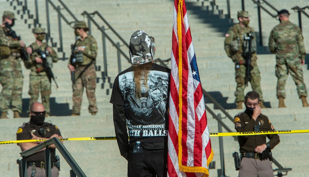 (Rick Egan | Tribune file photo) One of a dozen protesters carries an upside down flag at the Utah Capitol around noon on Sunday, Jan. 17, 2021, as beefed-up security guards the building. Lawmakers gave final approval to a bill that would expand security protection for lawmakers, their staff and even candidates who may face threats of violence.