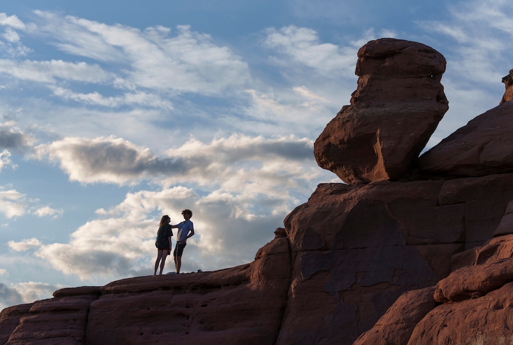 (Leah Hogsten | The Salt Lake Tribune)  Visitors to Delicate Arch in Arches National Park hang out around the Entrada Sandstone formation as the sun sets, Tuesday, May 16, 2023. In April 2023, Arches National Park implemented a timed entry system to pace visitors' arrival times to alleviate overcrowding and congestion among some 1.8 million visitors a year.