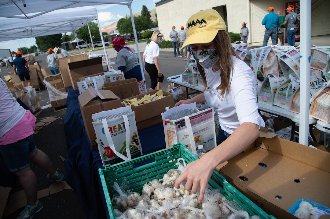 (Francisco Kjolseth  |  The Salt Lake Tribune) Paige Smith lends a helping hand as the third “Miracle Project” for the nonprofit foundation which raises money to purchase food produced by Utah farmers and then gives to residents in need, takes place at the Utah State Fairpark in Salt Lake City on Monday, July 27, 2020. The food donation from the Utah Farm Bureau’s “Farmers Feeding Utah” program provided food for 600 individuals and families who have recently become unemployed due to the coronavirus.